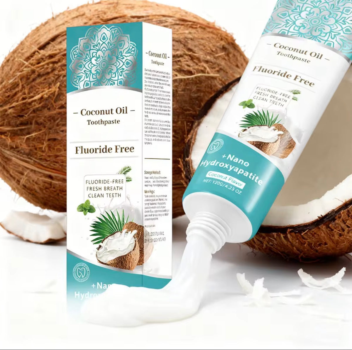 Coconut Oil Toothpaste tube and box shown with a dollop of white toothpaste on a clean white background, styled with whole and halved coconuts.